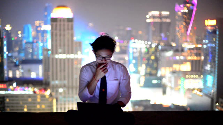 Young business man using laptop and look to cityscape, asian